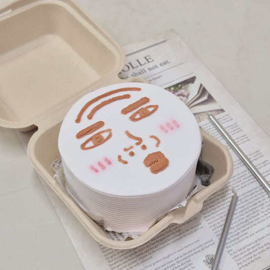 White mini bento cake with an image of a puckered face